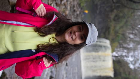 Primer-Plano-De-Una-Mujer-Excursionista-Sonriente-Con-La-Cascada-Sgwd-Yr-Eira-Detrás-De-Ella-En-El-Parque-Nacional-De-Brecon-Beacons,-Gales