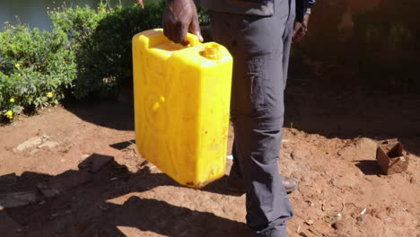 a person carrying a yellow water container outdoors in africa