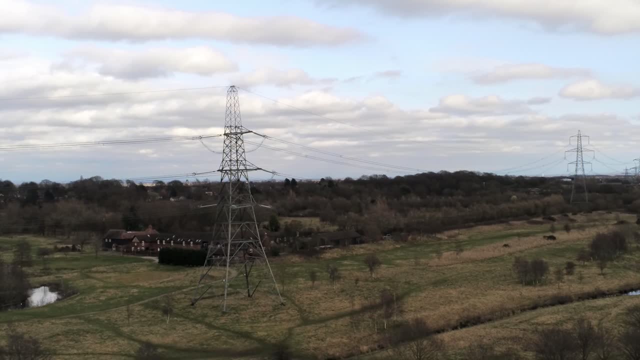 Low aerial view flying Electricity distribution power pylon overlooking British parkland countryside