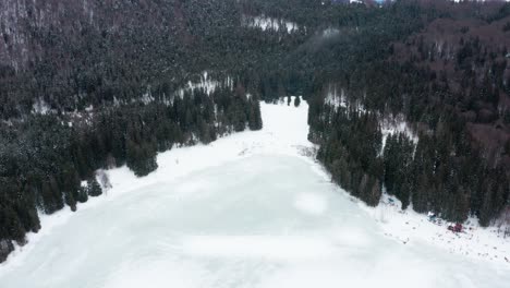 Lago-De-Cráter-Volcánico-Congelado-Aislado-En-El-Bosque,-Sfanta-Ana,-Rumania,-Drone-Inclinado-Hacia-Abajo