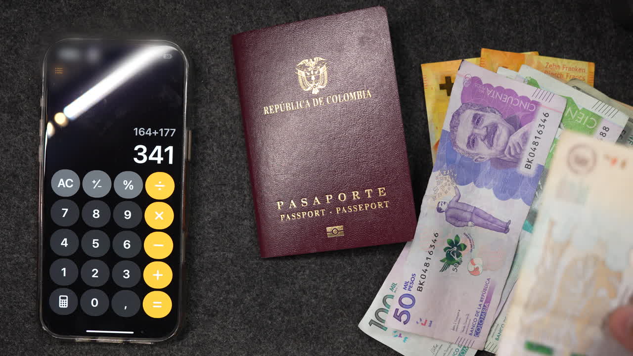 Kolumbijský pas s pesy a kalkulačkou na chytrém telefonu na tmavé látce. Živá měna dodává vizuální zajímavost pod jemným stropním osvětlením. V záběru nejsou žádní lidé.