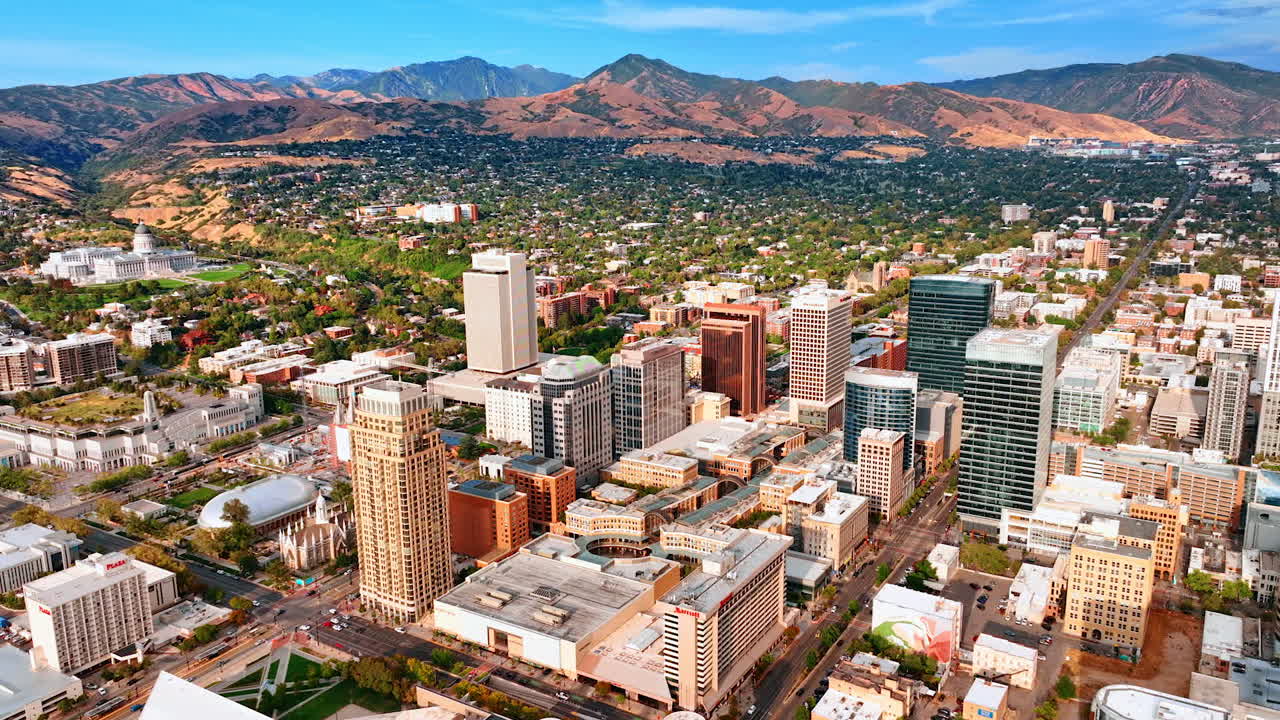 Salt Lake Sity USA, 14 August 2025: Beautiful downtown of Salt Lake City, Utah, USA. Drone footage descending over the city. Mountains with green residential area at the foot in the backdrop
