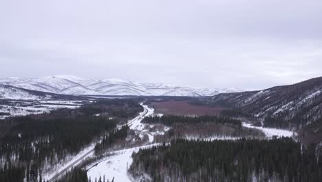 aerial alaska wilderness landscape, snow covered hills, green spruce