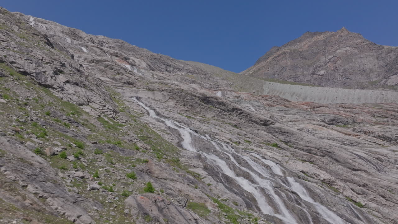 Two hikers explore Saas-Fee, Saas-Balen, and the Saas-Almagell dam, passing waterfalls, marmots, and alpine peaks in a breathtaking high-mountain landscape.