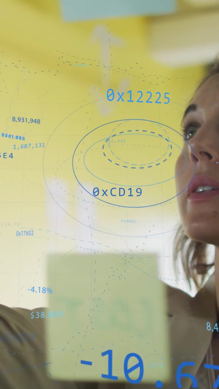 Vertical video: Woman studying blue data, placing sticky note, marking glass for business review