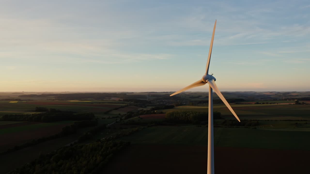 Turbina eolica su paesaggio rurale all'alba/tramonto