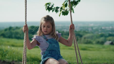 Blonde-girl-swinging-high-in-summer-day.