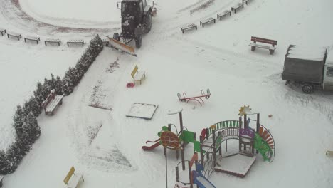 tractor-excavator removes snow in the city yard. work of public utilities