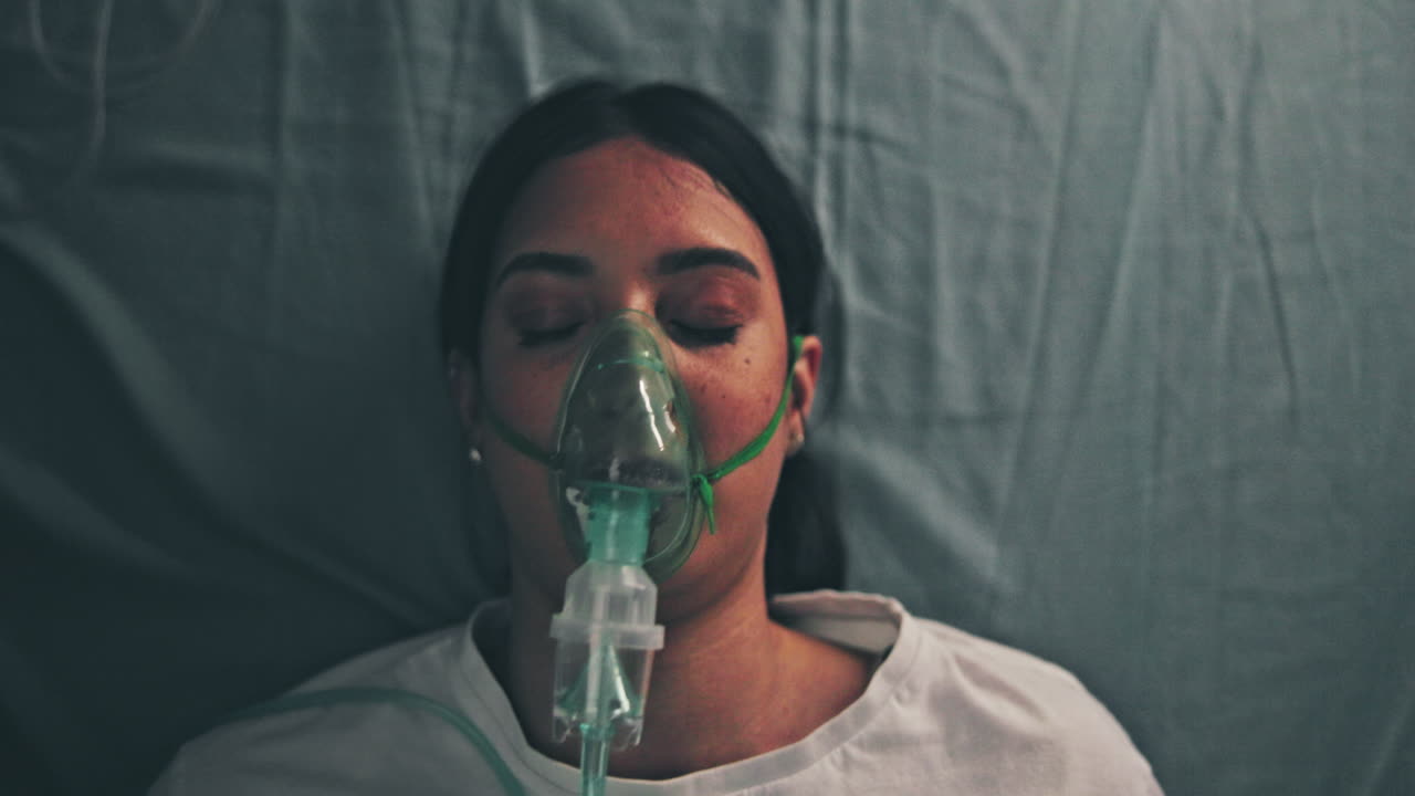 Woman wearing oxygen mask in hospital bed