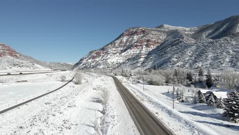 aerial footage flying along the grand army of the republic highway with i-70 and mountains in the background