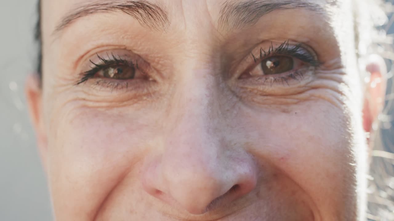 retrato de primer plano de los ojos de una feliz mujer caucásica mayor inalterada sonriendo en cámara lenta.