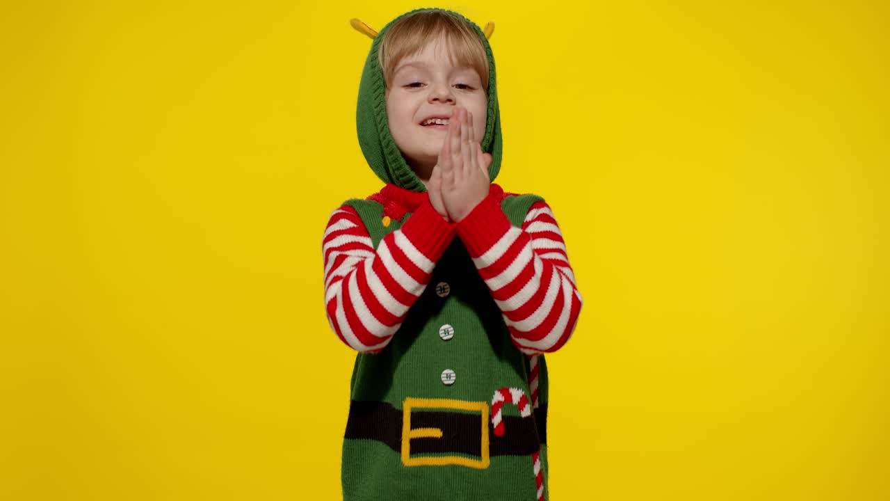 Dítě v kostýmu vánočního skřítka, pomocníka Santa Clause, prosí o dárky na Nový rok. Drží dlaně u sebe