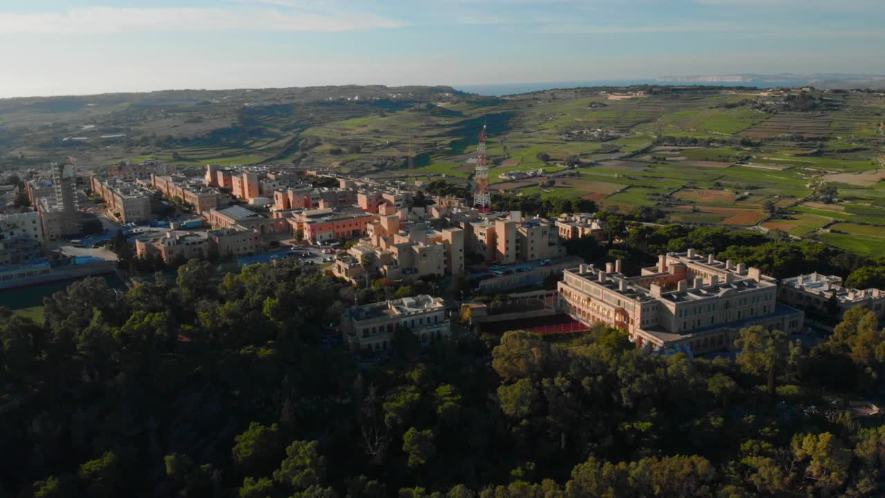 Veduta aerea di un paesino su una collina in campagna al tramonto.