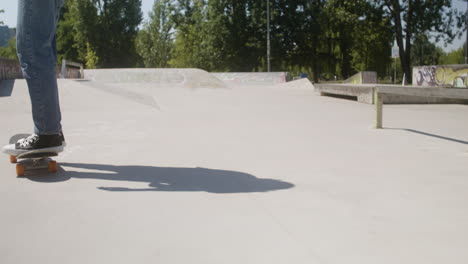 die füße eines jungen auf einem skateboard im skatepark.