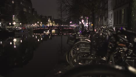 canal de ámsterdam con bicicletas en primer plano por la noche en los países bajos en los fríos canales de invierno