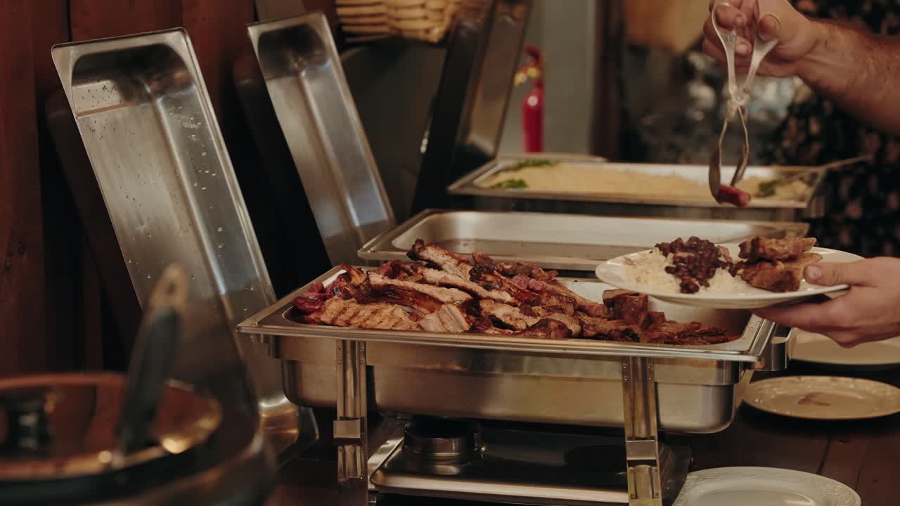 Grilled meat and rice served from buffet trays during indoor meal event location irrelevant