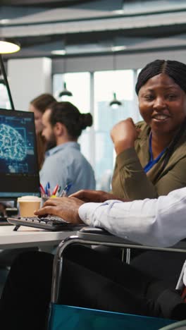 vertical video joyous technician with disability and coworker chatting while coding ai