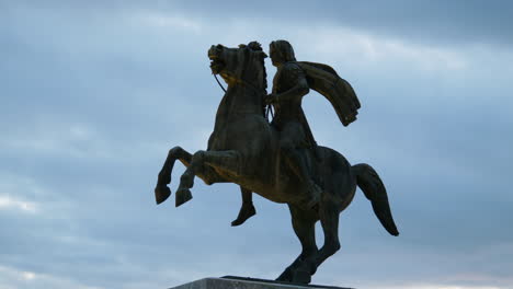 rearing horse statue of alexander the great seen at golden sunset in thessaloniki with seaside background and visitors.
