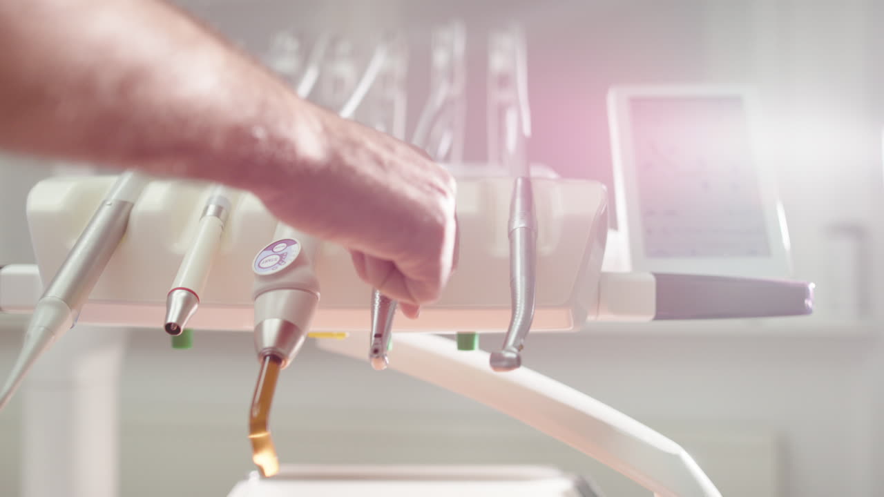 Closeup in dentist office of hand choosing dental tool from selection, oral care