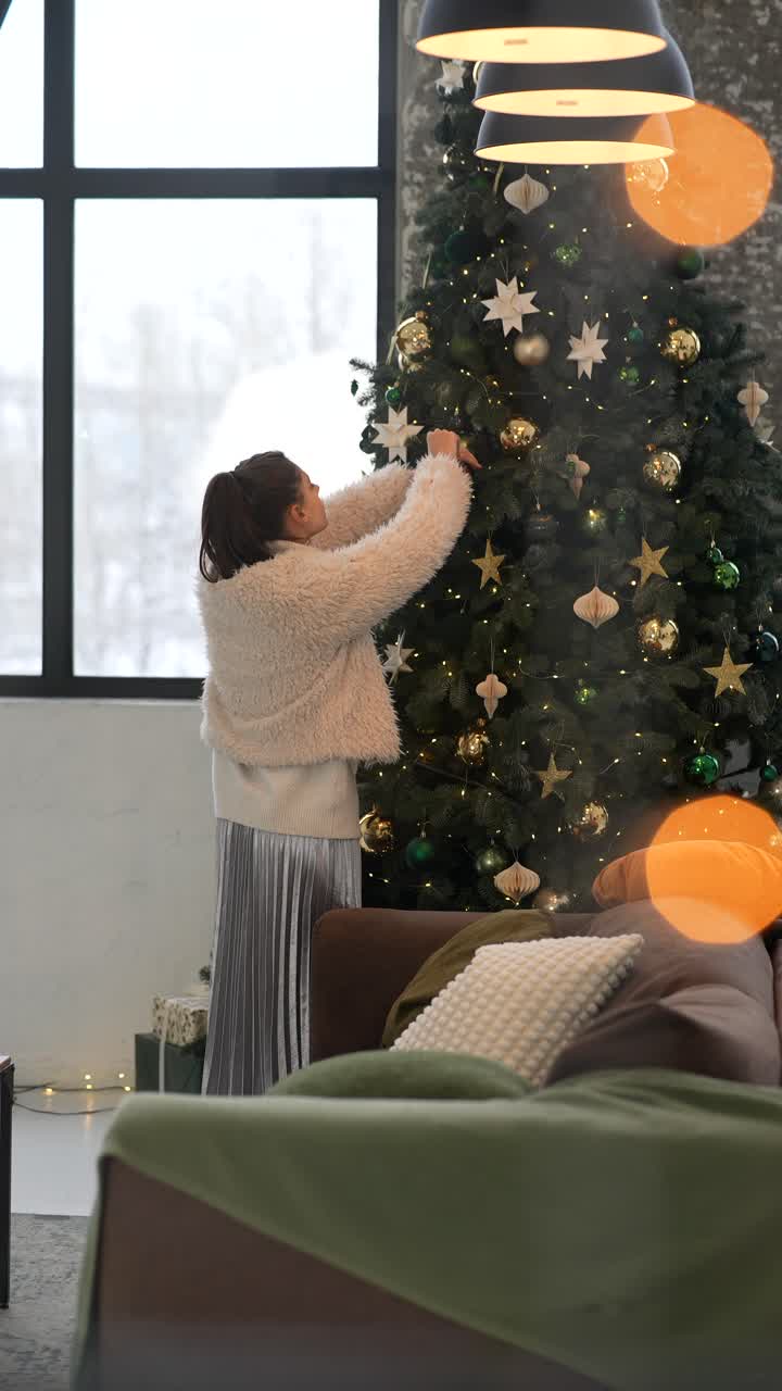 mujer decorando el árbol de navidad en la acogedora sala de estar