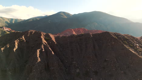 Flying-over-a-mountain-and-revealing-the-village-of-Purmamarca-on-a-beautiful-sunset-in-Jujuy,-Argentina