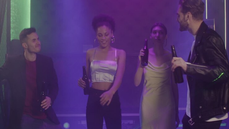 Group Of Four Young Friends Holding Beer And Dancing At Disco