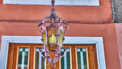 cinemagraph loop: hanging lamp hangs in arch to old building and swings in wind