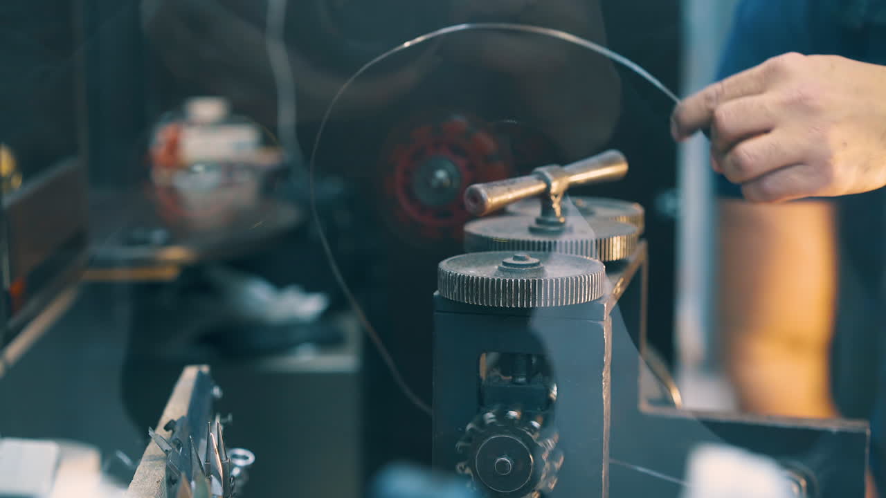 trabajador gira el mango de la máquina de laminado de forja con varilla de oro