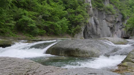 slow motion tilt up over wide river basin at fukiware falls in japan