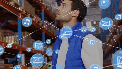 Animation-of-network-of-digital-icons-over-caucasian-male-supervisor-checking-stock-at-warehouse