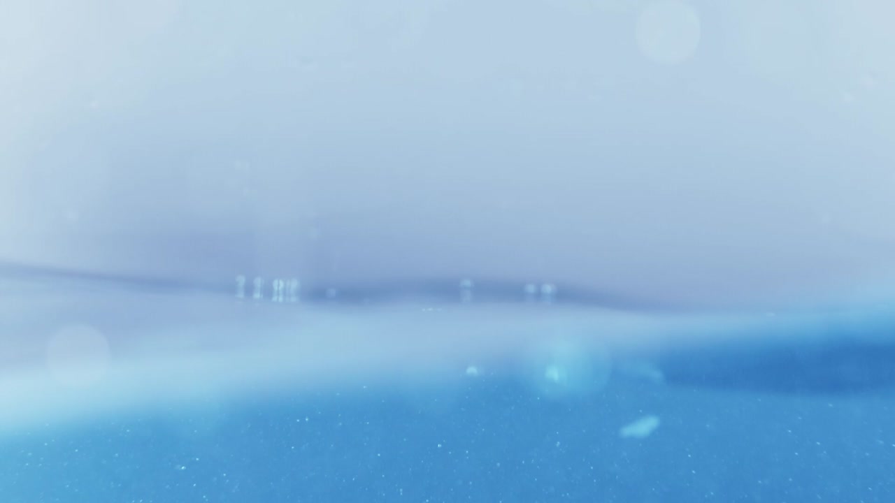 슬로우 모션의 깨끗한 물 표면은 물이 튀는 상점으로 화면을 채우고 기포로 액체 표면을 흔들고 있습니다.