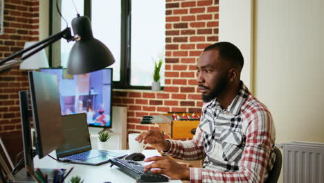 male coder works from home typing code on a laptop in a modern living room