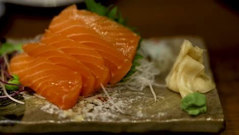 salmon sashimi being picked up with chopsticks