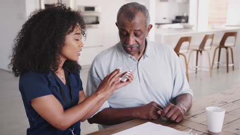 Female-healthcare-worker-showing-a-senior-man-how-to-use-an-assistance-alarm-during-a-home-visit