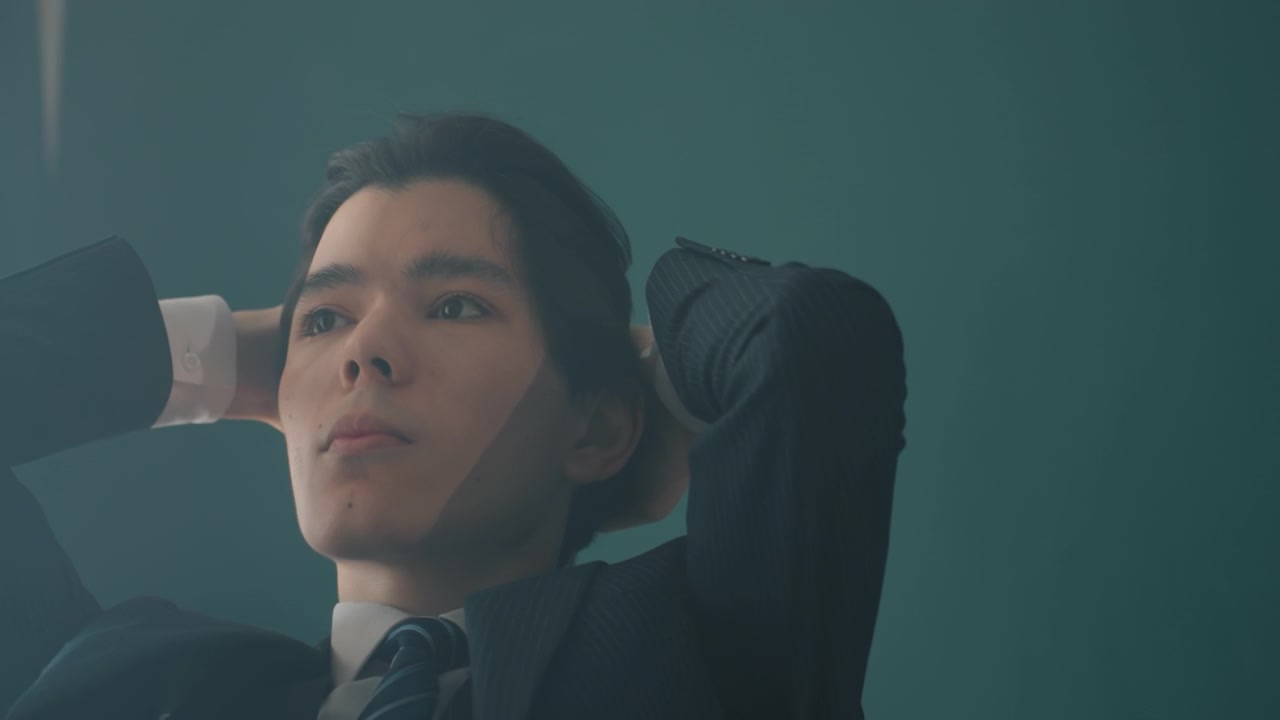 एशियाई व्यवसायी सिर के पीछे हाथ रखकर लेटा हुआ, नरम टील कार्यालय की रोशनी, सूट और टाई, चिंतनशील नज़र, कार्यकारी रणनीति पर विचार कर रहा है, उद्यमी प्रबंधक डिजाइनर की भूमिकाएं फ्रेम में सुझाई गई हैं।