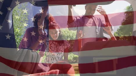 animation of flag of united states of america over diverse family by car during road trip