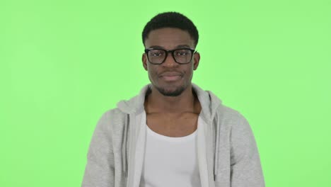 african man showing no sign by arm gesture on green background