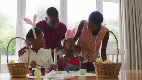 african american family painting easter eggs together at home