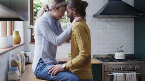 caucasian couple shares a tender moment in the kitchen, hugging