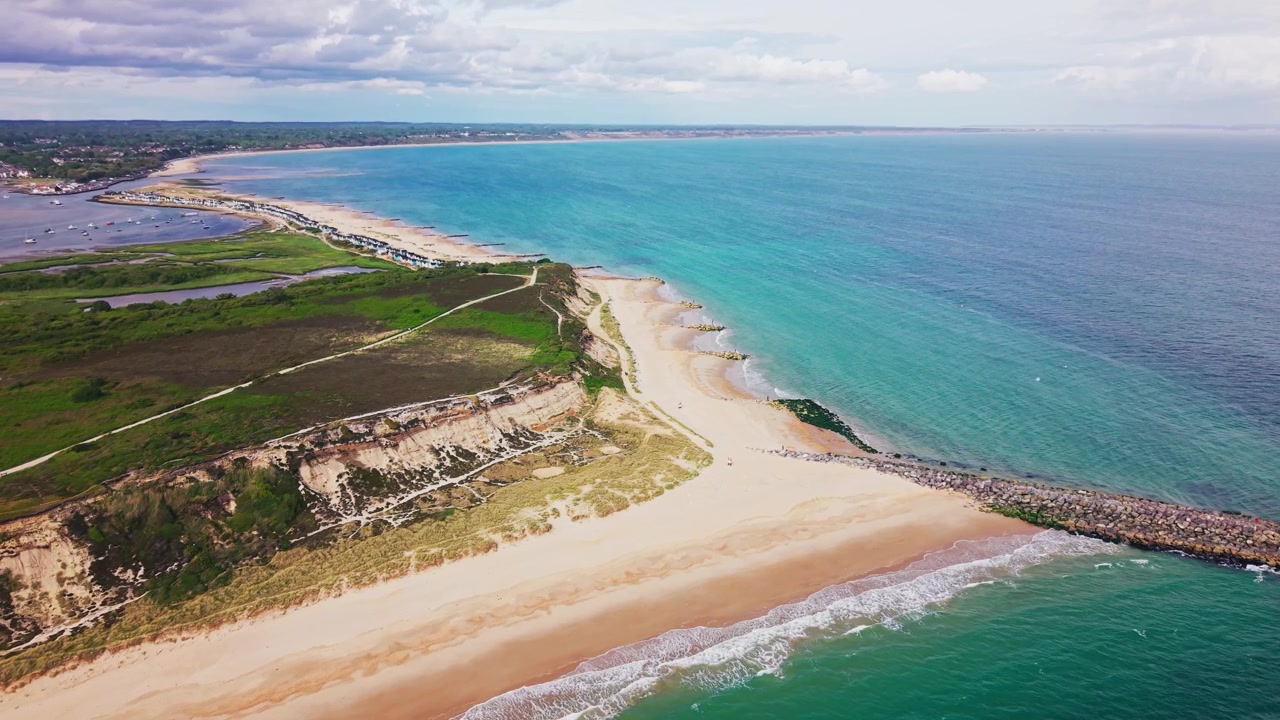 Droneoptagelser over Hengistbury Head med sandstrand, turkisblåt hav, stenmoler, kystklipper, hede og Christchurch Harbour