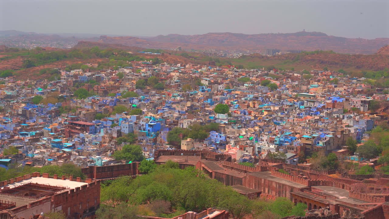 インド、ラージャスターン州。澄み切った空の下、メヘラーンガル城の古代の石壁に囲まれたジョードプルの広大な青い家々を見下ろす広角の静止画