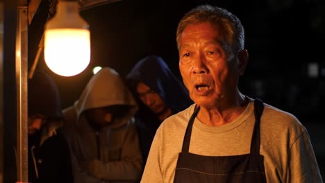 an experienced vendor prepares his delicacies under a warm glow, while patrons await their turn, evoking a sense of community and tradition in the night market atmosphere.