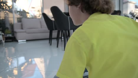 blond boy with curly hair sitting on the floor playing with his dog and a ball