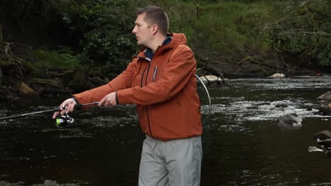 Slow-motion-shot-of-a-fisherman-casting-a-spinning-rod-into-a-stream-carrying-a-net