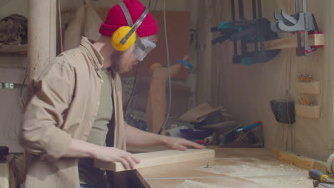 Woodworker in Safety Earmuffs and Glasses Using Trimmer Table