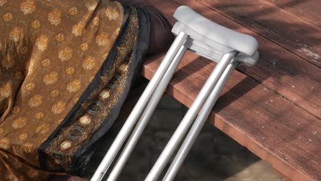 woman with crutches resting on a wooden table