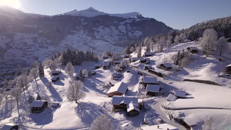 pushing in over terrassenweg over snow covered houses and trees in grindelwald, views of maennlichen