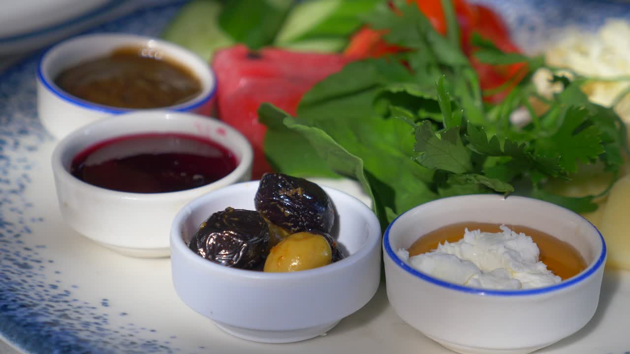 Turkish breakfast plate with olives, cheese, honey, jam, tomato, cucumber, watermelon and greens