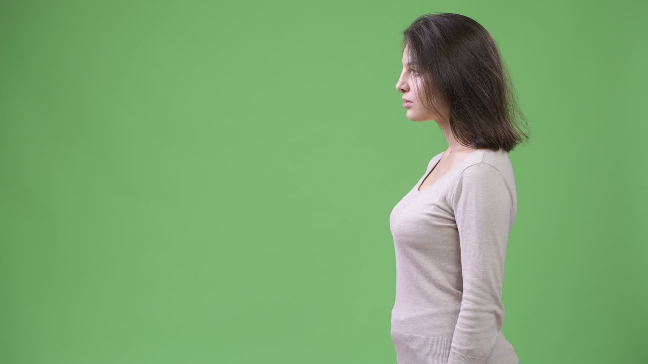 Profile view of young beautiful woman against green background