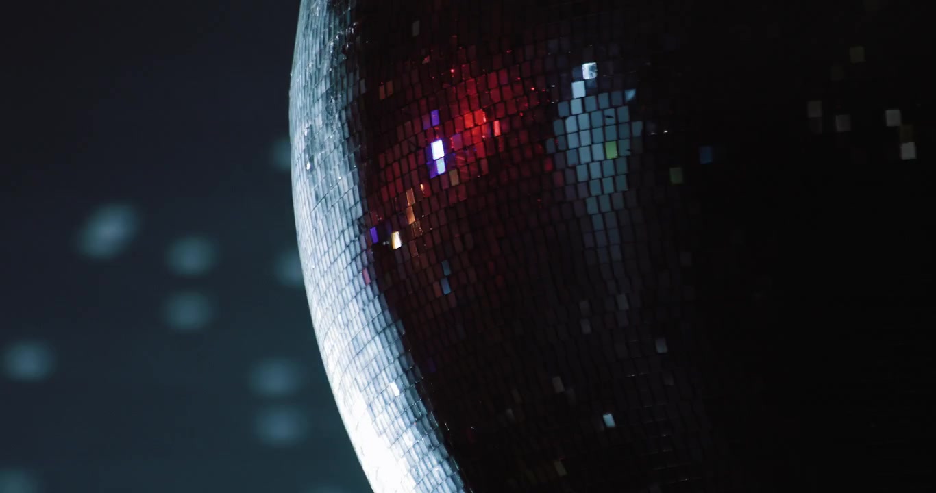 Palla da discoteca rotante che riflette luci colorate in una stanza buia